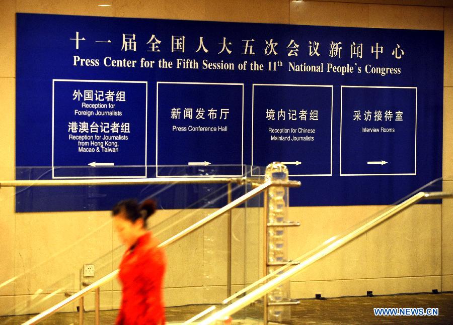 A staff worker walks past a signboard of the Press Center for 'Lianghui', namely the two annual sessions of the National People's Congress (NPC) and the National Committee of Chinese People's Political Consultative Conference (CPPCC), in Beijing, capital of China, Feb. 26, 2012. 