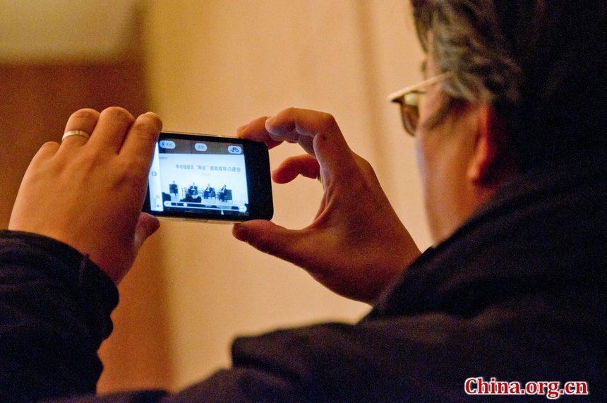 A journalist takes pictures of Li Shufu and other speakers during the press conference held by Geely on Friday, March 2, 2012, one day before the CPPCC formally starts on Saturday. [China.org.cn]