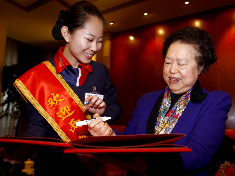 Tam Wai-chu (R), a deputy to the Fifth Session of the 11th National People's Congress (NPC) from south China's Hong Kong Special Administrative Region, gives an autograph to a staff member as she arrives in Beijing, capital of China, March 2, 2012. 