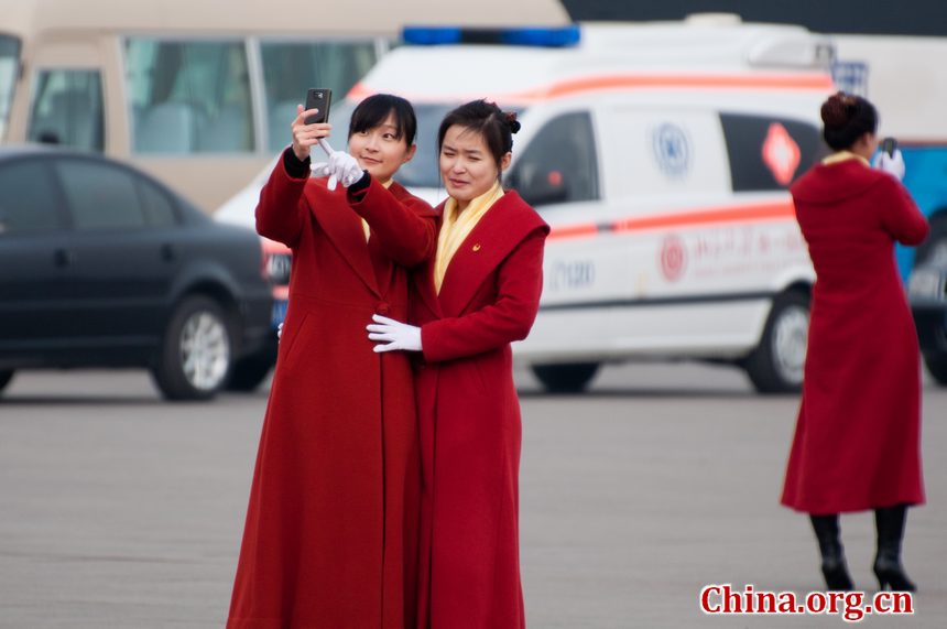 Hotel staff members serving the delegations to the National People's Congress (NPC) pose for self photos at the Tian'anmen Square on Sunday, March 4, 2012, in Beijing, China, one day prior to the NPC's opening ceremony on the morning of March 5 at the Great Hall of the People. Their poses attract photojournalists from both home and abroad. [China.org.cn]