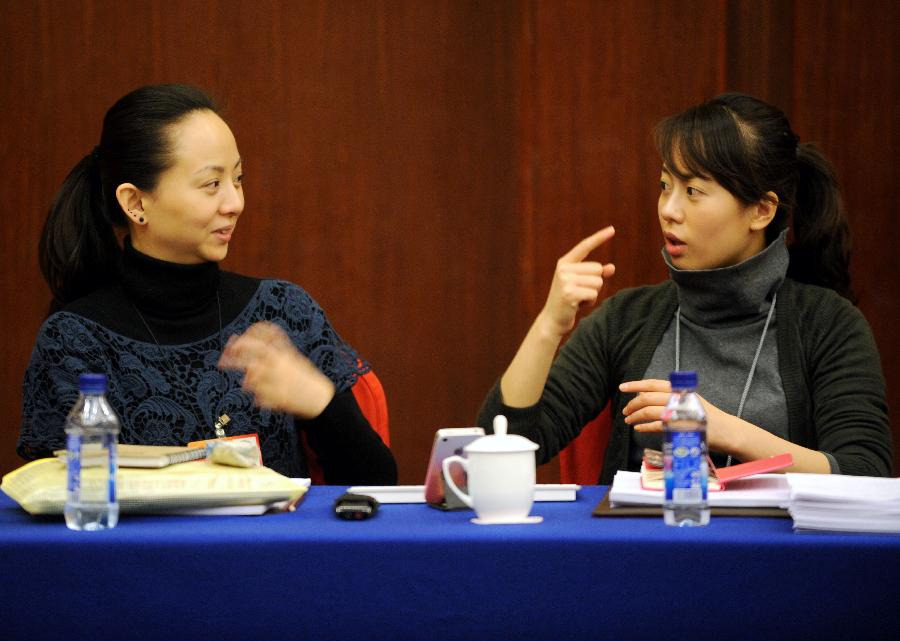 Tai Lihua (L), a member of the 11th National Committee of the Chinese People's Political Consultative Conference (CPPCC), joins in a panel discussion of the Fifth Session of the 11th CPPCC National Committee with the help of a sign language interpreter in Beijing, capital of China, March 4, 2012.