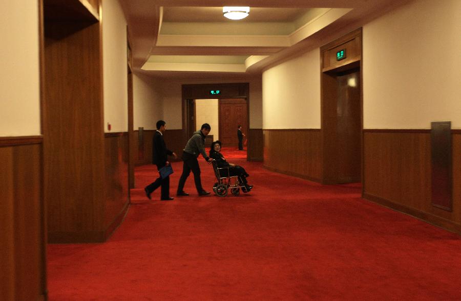 Wan Shanhong (in wheelchair), a member of the 11th National Committee of the Chinese People's Political Consultative Conference (CPPCC), leaves the conference hall in the Great Hall of the People after the closing meeting of the Fifth Session of the 11th CPPCC National Committee in Beijing, capital of China, March 13, 2012. 