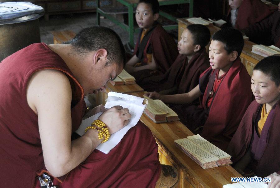 Dangzhou Cering (1st L) corrects students&apos; papers at the elementary school of Changu Monastery in Jiegu Town of Yushu Tibetan Prefecture, northwest China&apos;s Qinghai Province, March 17, 2012. 
