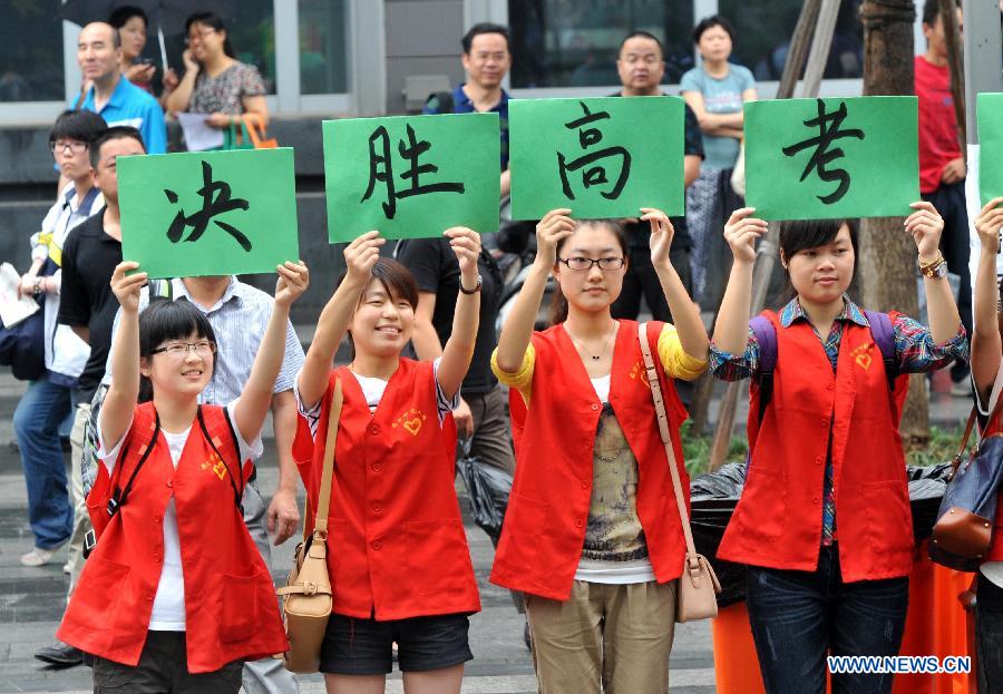 Volunteers hold a slogan 'Victory in Gaokao' outside Nanjing No. 9 Middle School in Nanjing, capital of east China's Jiangsu Province, June 7, 2012. 