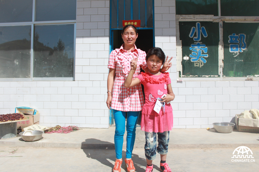 Chao Ailian (L), chief of the Female Credit Association in Qujiazhuang Village and her daughter (R) pose for a picture in front of their petty store in Qujiazhuang Village of Jiaxian County, northwest China&apos;s Shaanxi Province, June 10, 2012.