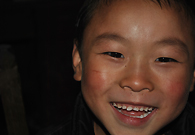 A boy was smiling to the visitors. To show his politeness, he washed his face. Due to the lack of electricity, the background is black.