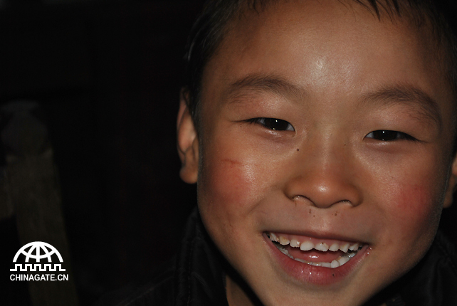 A boy was smiling to the visitors. To show his politeness, he washed his face. Due to the lack of electricity, the background is black. 