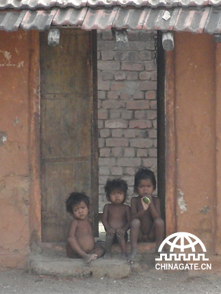 Three naked kids were sitting in front of the gate. Their family is too poor to buy clothes for them.
