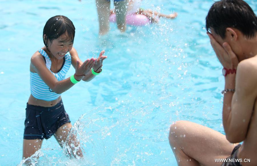 A student from Shuren School, a school for the children of migrant workers, plays with a volunteer during a charitable activity at a water park in Beijing, capital of China, Aug. 12, 2012.