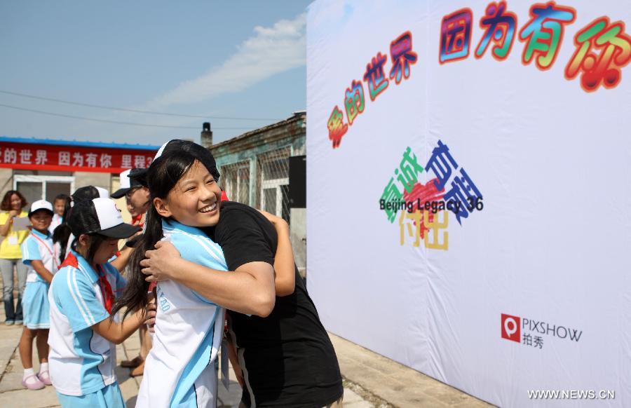 Students hug their donators during a charitable activity in Shuren School, a school for the children of migrant workers, in Beijing, capital of China, Aug. 12, 2012. 