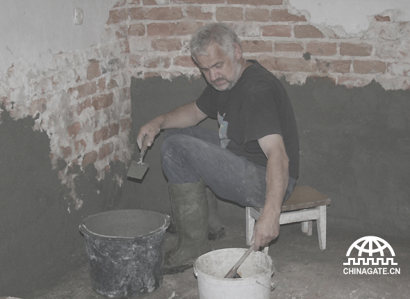 A volunteer repairs the wall in the old man’s home.