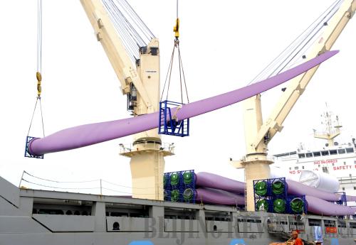 Workers load wind turbine blades to be exported overseas on board a ship at the port of Lianyungang in Jiangsu Province on May 25.