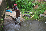 A man from a poor village is bathing in the river. He has no bath-room, and no bucket in his cottage.