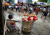 One morning after raining during Taungpyone Pagoda Festival,a young girl is selling some paper hats beside the muddy street in the Taungpyonegyi Village. She just counted the money in her hand. It could not be very much.