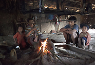 Photo shows a Narga family living in a small hut in Lahei, in Chin State in Myanmar. There is no living room, nor bed room or kitchen room. They live, eat and sleep only at one place, near the fire which is usually the centre of the hut.