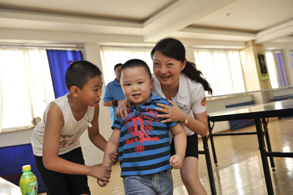 Cui Xiangqian, 42, plays with children at a community playroom in Guiyang, southwest China's Guizhou Province, Sept 10, 2012. 