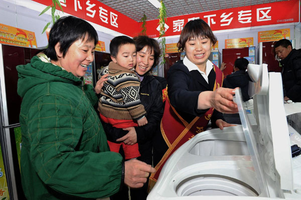 A saleswoman introduces washing machines to rural customers in Shunyi District, Beijing on March 12, 2010. 