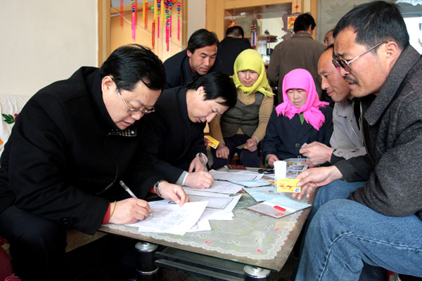 Bank clerks deal with a small loan application in a villager's home in Zhangye City, Gansu Province on May 30, 2010. 