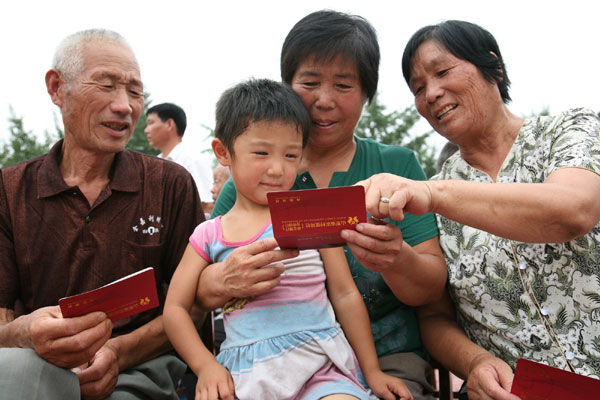 Villagers get pension deposit books under a new elderly insurance system for rural residents in Shouguang City, Shandong Province on Aug 19, 2009. 