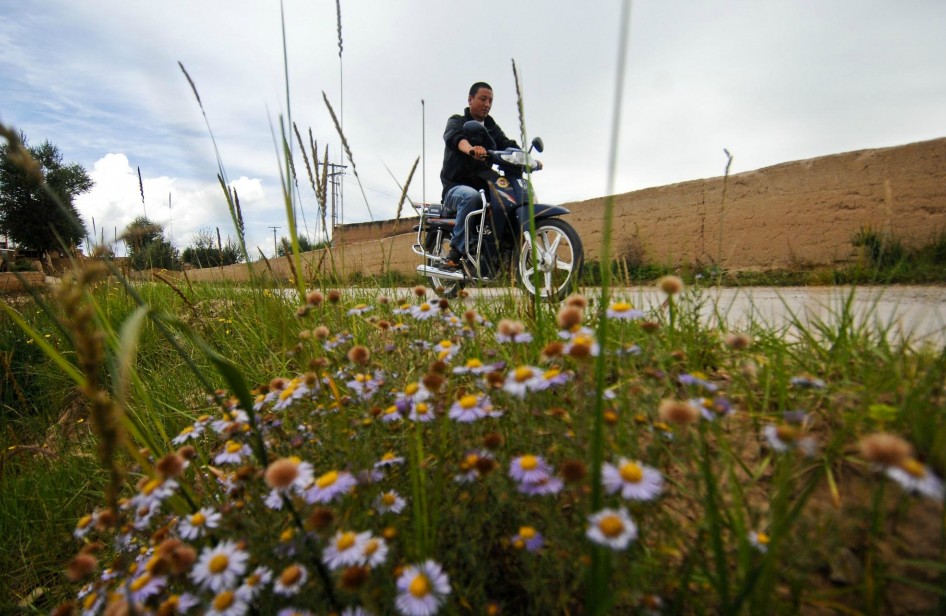 Nyima Tsering rides a motorcycle to visit famers in Jicang Village, Huangnan Tibet Autonomous Prefecture, Qinghai Province, Aug 22, 2012.