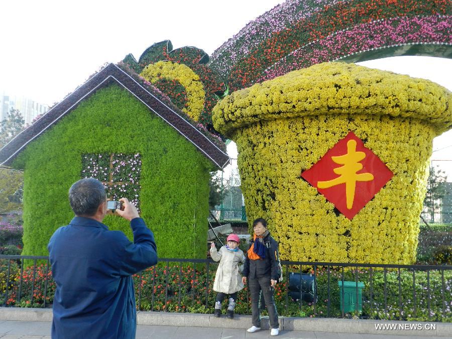 Visitors pose for photos in front of the flower decorations displayed on the street to greet the upcoming 18th National Congress of the Communist Party of China (CPC) in Beijing, capital of China, Oct. 30, 2012. 