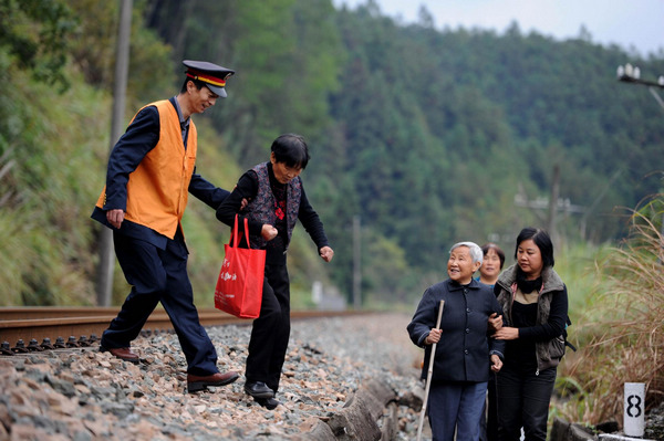 Li assists an old woman attempting to walk through in Qimen County, east China's Anhui Province, Oct 30, 2012.