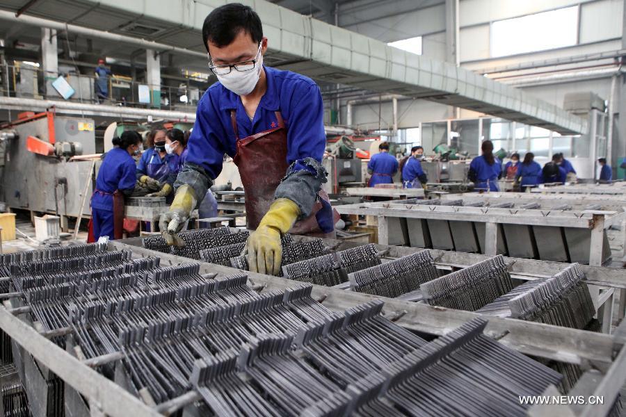 Workers produce battery lead plate at a company in Ganyu County, east China's Jiangsu Province, Oct. 31, 2012. 