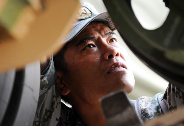 Jia Yuanyou, a delegate of the 18th CPC National Congress and artilleryman, repairs a tank in Beijing, June 28, 2011. [Xinhua] 