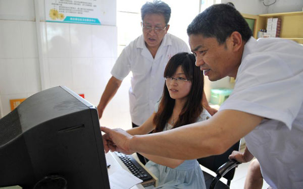 Zhong Yi (C) helps doctors solve internet problems at the clinic in Zhanfeng Village of Jiashan County, east China&apos;s Zhejiang Province, June 29, 2012.