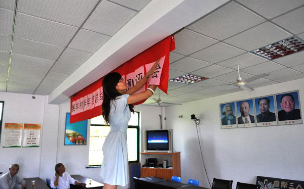 Zhong Yi hangs a banner prior to a mid-year summarizing meeting in Zhanfeng Village of Jiashan County, east China&apos;s Zhejiang Province, June 29, 2012.