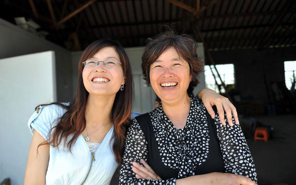 Zhong Yi (L) smiles with Feng Linhua, deputy director of the village committee and her kindergarten teacher, in Zhanfeng Village of Jiashan County, east China&apos;s Zhejiang Province, June 29, 2012. 