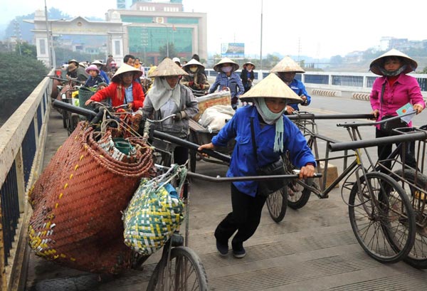 Border residents from Lao Cai Province of Vietnam pass the Hekou road bridge to sell their goods in Yunnan Province on Dec 17, 2009. 