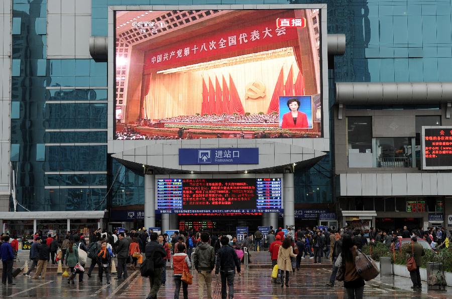 Passengers watch TV reporting the opening ceremony of the 18th National Congress of the Communist Party of China (CPC) at the railway station in Guiyang, capital of southwest China's Guizhou Province, Nov. 8, 2012.