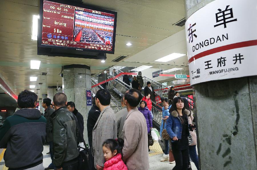 Subway passengers watch TV reporting the opening ceremony of the 18th National Congress of the Communist Party of China (CPC) in Beijing, capital of China, Nov. 8, 2012. 