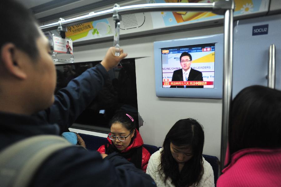 Subway passengers watch TV reporting the opening ceremony of the 18th National Congress of the Communist Party of China (CPC) in Beijing, capital of China, Nov. 8, 2012. 