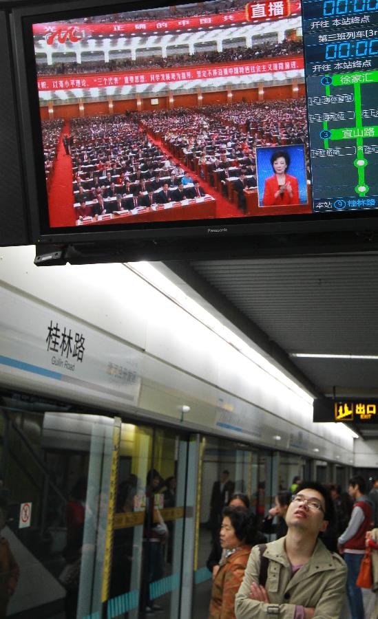 A subway passenger watches TV reporting the opening ceremony of the 18th National Congress of the Communist Party of China (CPC) in east China's Shanghai, Nov. 8, 2012. 