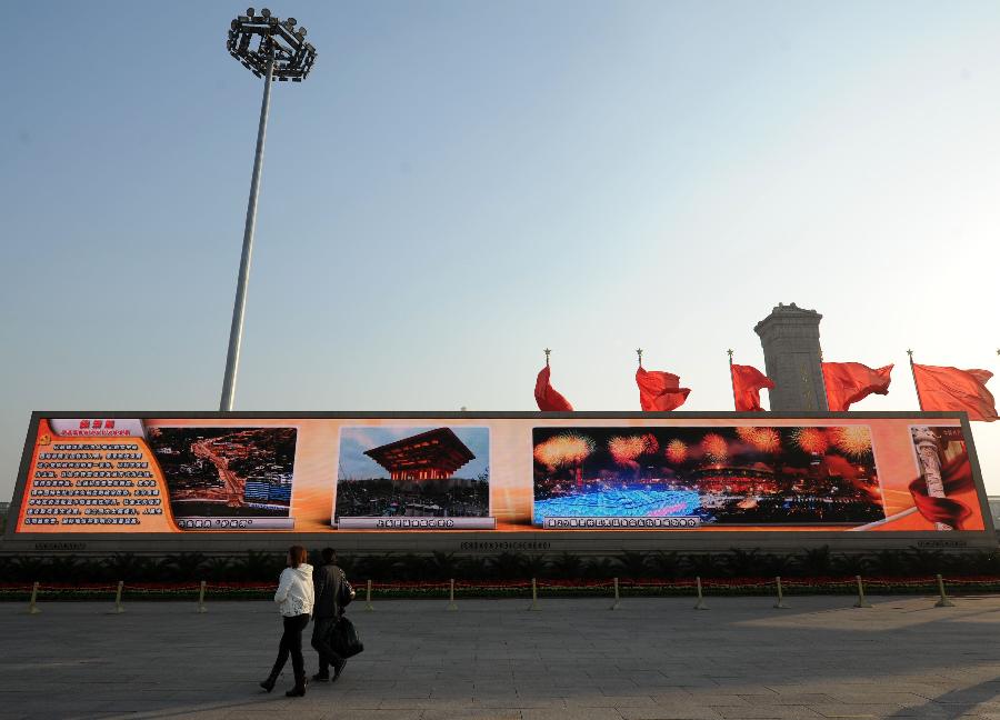 Visitors watch a large screen displaying achievements which China has gained under the leadership of the Communist Party of China (CPC) in the past decade, at the Tian'anmen Square in central Beijing, capital of China, Nov. 8, 2012.