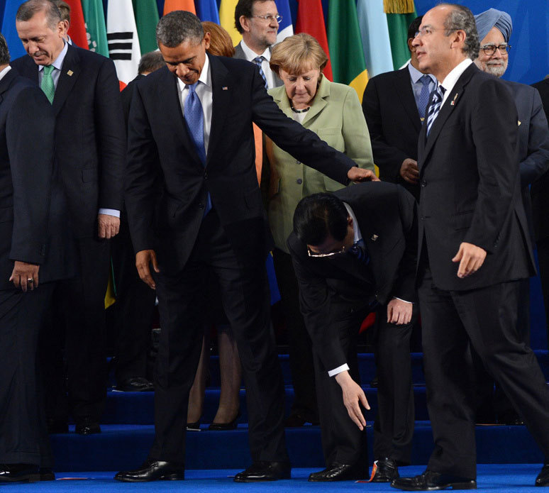 Chinese President Hu Jintao (2nd, R) bends down to pick up a Chinese national flag sticker which has been used to mark his spot for a group photo at the G20 Summit in Los Cabos, Mexico on Jun. 18, 2012.