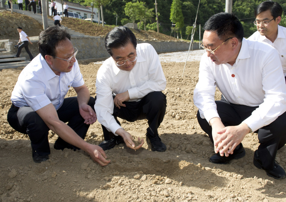 Chinese President Hu Jintao checks the soil moisture in a farming field suffering from drought and sows corn seeds together with farmers in Hubei Province, during an inspection tour between May 31 and Jun. 3, 2011. 