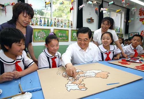 Chinese President Hu Jintao (C) stays with the pupils at Jushan Primary School in Haidian District, Beijing to make a map of China with eggshells on May 31, 2009, right before the International Children&apos;s Day.