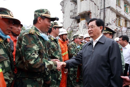 Chinese President Hu Jintao shakes hands with a military officer while inspecting the disaster relief work in the quake-stricken Xuankou Town in Wenchuan County, Sichuan Province, on May 17, 2008.