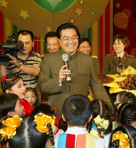 Chinese President Hu Jintao (C) extends his greetings to Chinese children one day ahead of the International Children's Day, after watching a song-and-dance performance by children from the Little Red Star Kindergarten Art Troupe, at China Theater in Beijing on May 29, 2005.