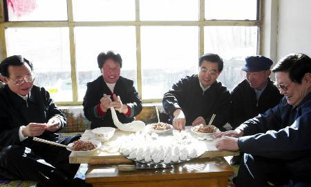 Chinese President Hu Jintao (C) makes dumplings with farmer Lu Zhanlin and his family at Lu's home in Xishungou Village of Zhangbei County, during his inspection tour of Zhangjiakou City, Hebei Province on Jan. 20-21, 2004.