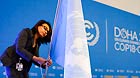 A woman installs a UN flag in the assembly room of the climate change conference at the Qatar National Convention Center in Doha on Nov 25, 2012