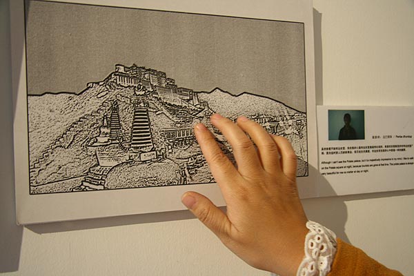 A blind girl touches a Braille typed photo of the Potala Palace. [CnDG by Jiao Meng]