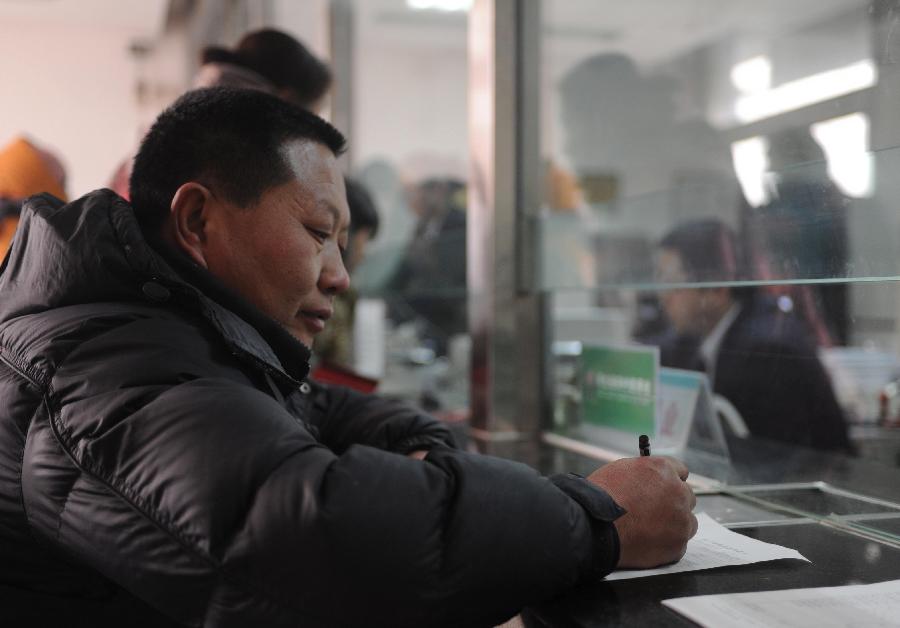 A farmer fills in an application form for small personal loans at the Rural Credit Cooperative of Gaoling Township in Wangdu County, north China's Hebei Province, Jan. 12, 2013.