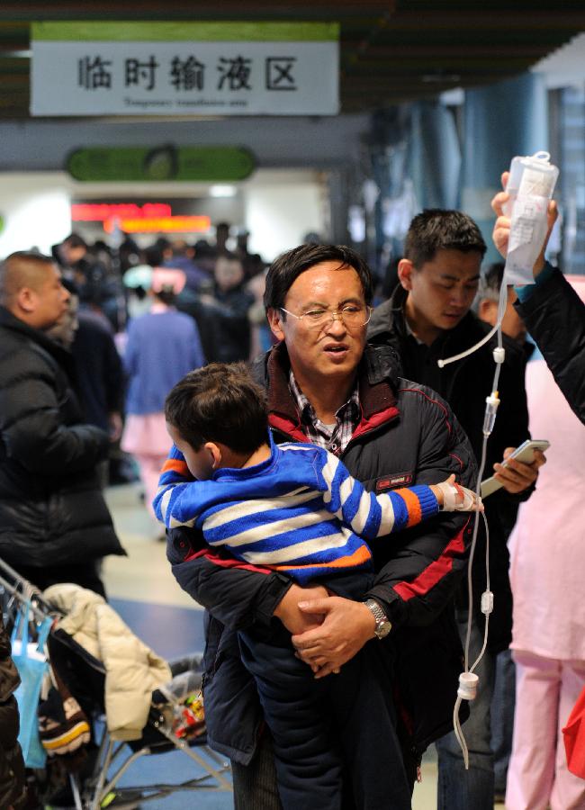 A man holding a child looks for an empty seat at the temporary transfusion area of Beijing Children's Hospital in Beijing, capital of China, Jan. 13, 2013. 