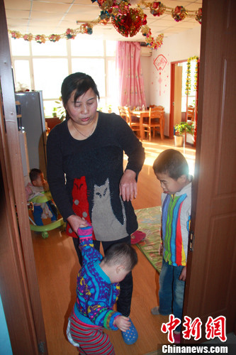 A caretaker with four orphans stands in a room at the Hohhot Children’s Welfare Institute. 