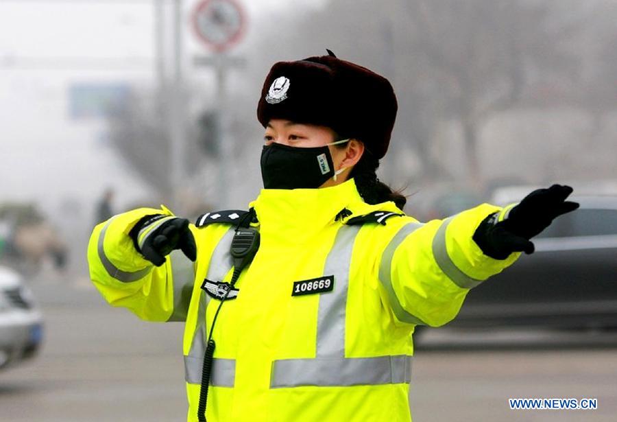 A traffic policewoman with a mask directs the traffic in Jinan, capital of east China's Shandong Province, Jan. 30, 2013. The local traffic policemen used masks to protect their health in hazy days.(Xinhua/Xu Suhui) 