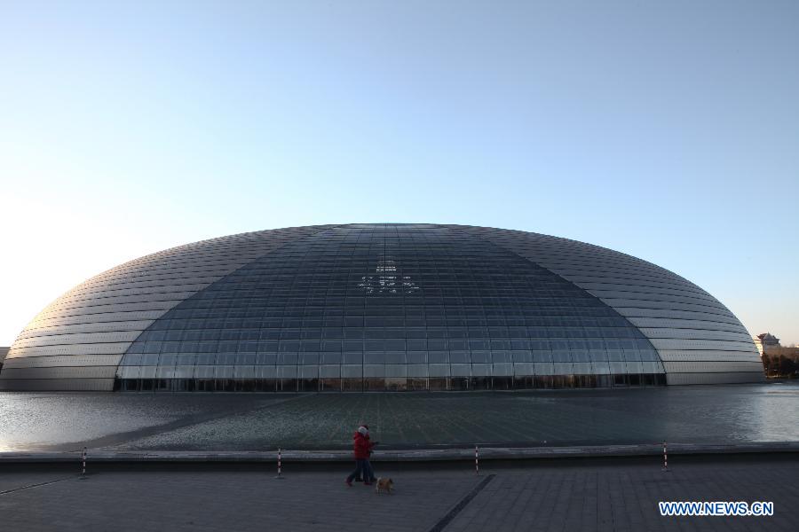 Citizens walk a dog besides the National Centre for the Performing Arts in Beijing, capital of China, Feb. 1, 2013.